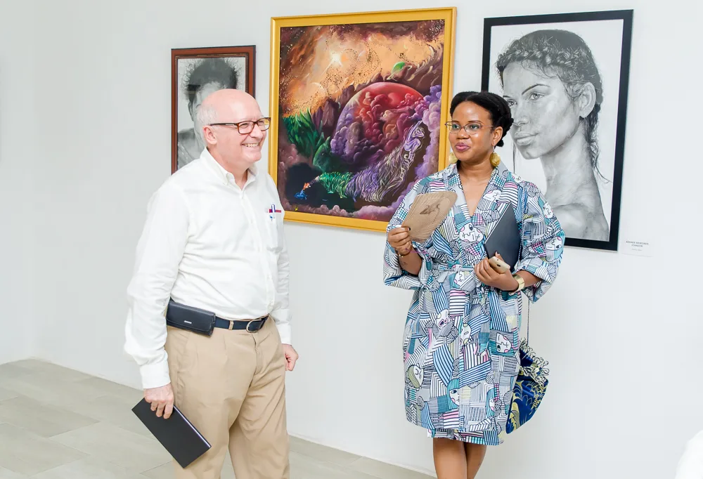 Guests in conversation beside artworks at a Jade Art exhibition opening.