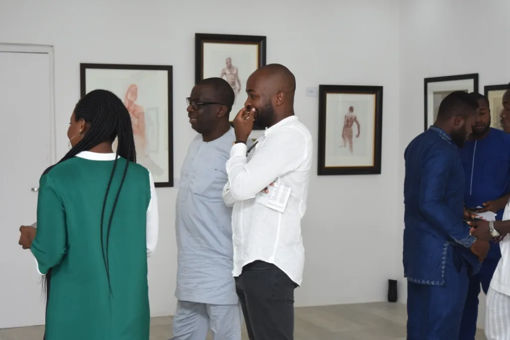 Visitors exchanging ideas among framed works in the gallery.