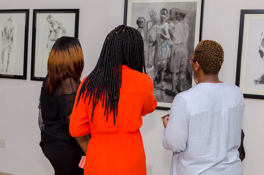Guests studying a large figurative drawing in the gallery.