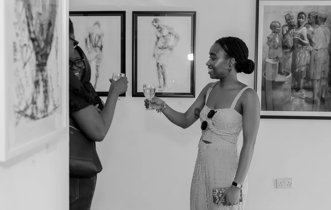 Two guests sharing a toast surrounded by figurative artworks.
